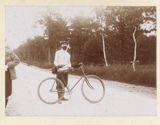 Man posing with a bicycle on a road in France