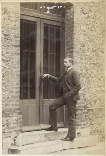 Portrait of a young man standing by a closed door in France