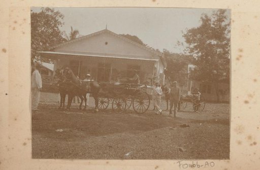 Dutchmen by a cart, driven by an Indonesian man, in front of a house