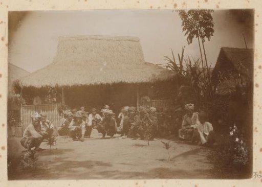 Dutch East Indies, group portrait of Indonesian men in front of a house with a thatched roof