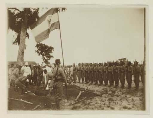 Military funeral with African honor guard, flag and (probably) Germans in Cameroon