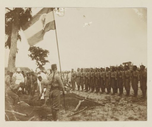 Military funeral with African honor guard, flag and (probably) Germans in Cameroon
