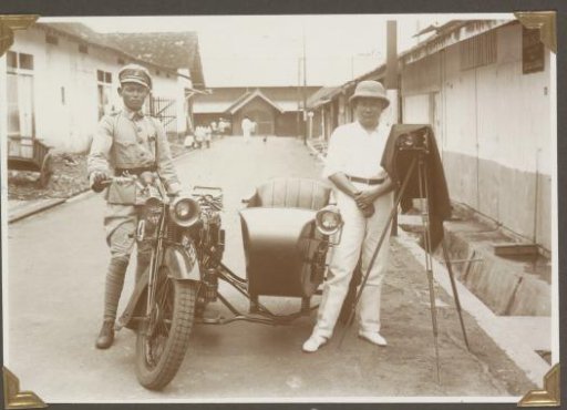 Portrait of the regional police photographer in Lampong, standing next to his camera with an assistant
