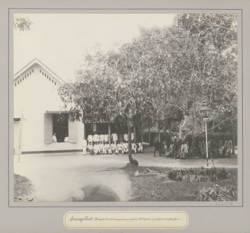 Patients, European physician Dr. Djawa and assistant posing in front of a hospital in Soengeiliat
