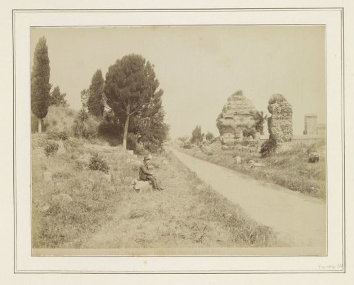 Man seated near remains of buildings on the Via Appia in Rome