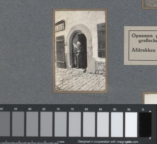 Old woman with a spinning wheel in a doorway
