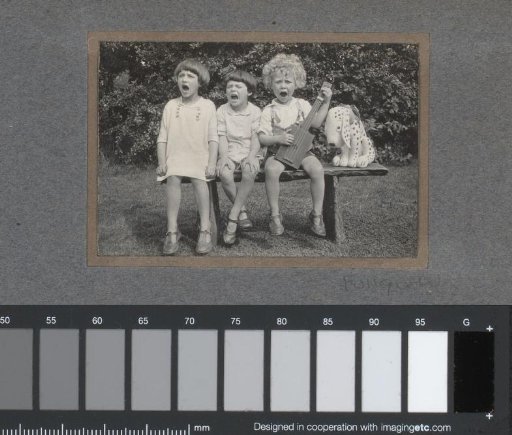 Singing children outside, seated on a bench