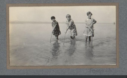 Three children in the water with sticks