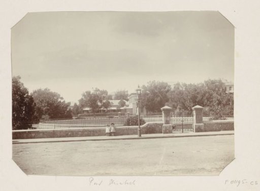 Two girls in front of the fence of a building (presumably) in Port Elizabeth