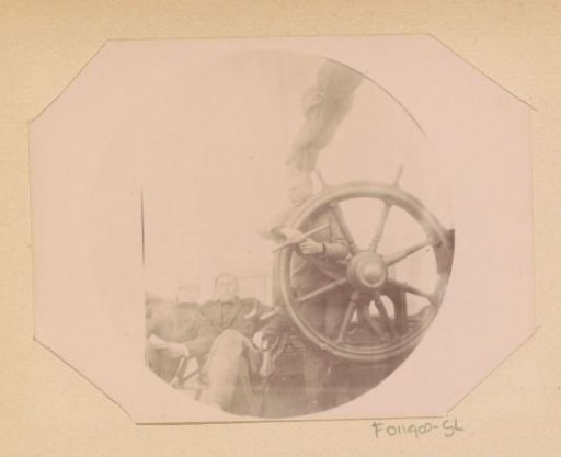 Three boys from the Public Trade School on the deck of a ship during an excursion to the Baltic Sea, one posing with binoculars behind a ship's wheel