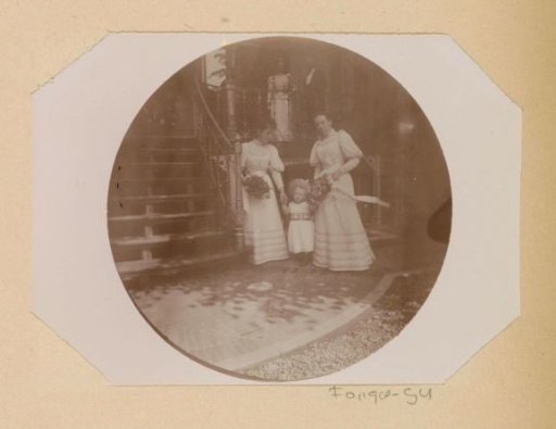 Cato Piek-Asser, standing at the top of an outside staircase next to an unknown man during her wedding, at the bottom of the staircase stands Gesiena Piek with an unknown woman and child