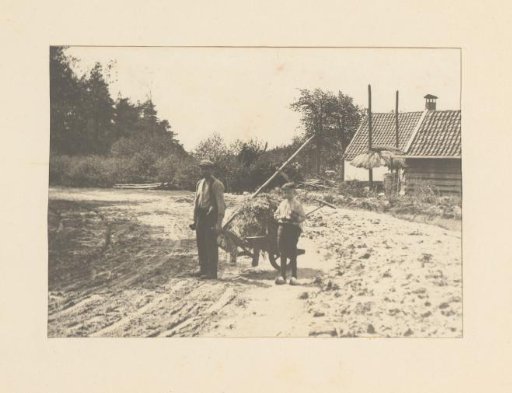Man and boy with a wheelbarrow on a farmyard