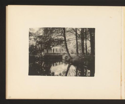 View of a house in a forest with a pond in the foreground