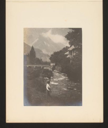 View of a mountain stream with a woman in the foreground and a bridge in the background