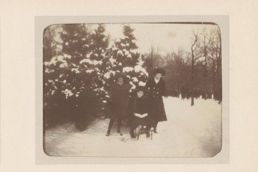 Group portrait of three young women with a sleigh, with a crowd in the background