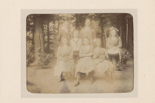 Group portrait of four girls and a boy and two young men in a garden