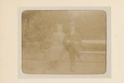 Portrait of a young man and young woman, sitting on a bench in a garden or park