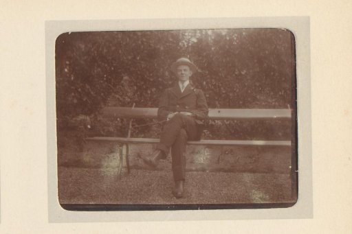 Portrait of a young man sitting on a bench in a garden or park