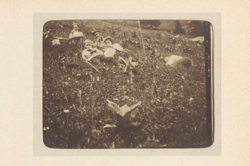 Two women and three children resting in a field