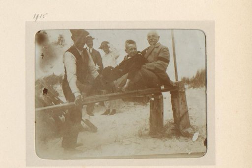 Older Man and Boy Sitting on a Wooden Fence, Three People Standing Behind