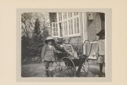 Portrait of a Toddler in a Carriage, Two Children Beside