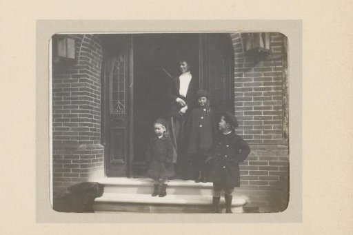 Portrait of a woman and three children on a stoop in front of a front door