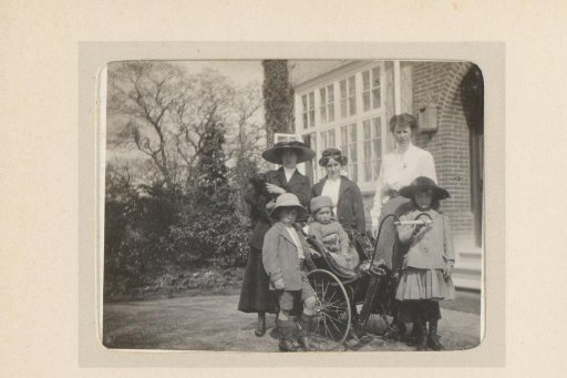 Portrait of three women and three children in front of a house