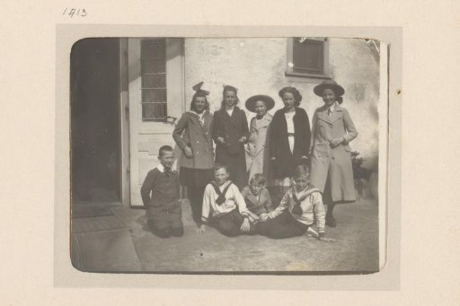 Group portrait of a company with children and youths in front of a facade