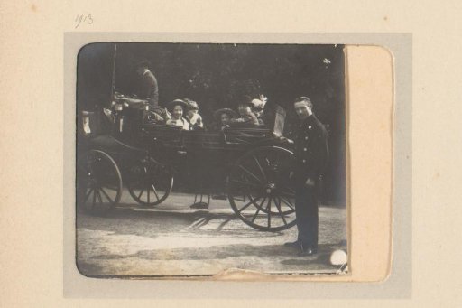 Group in a carriage, a man standing beside it