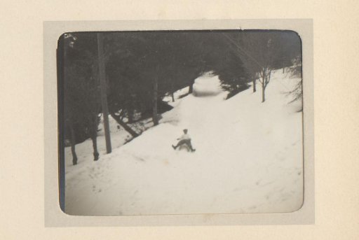Boy or Man Sliding Down a Snowy Mountainside on a Sled