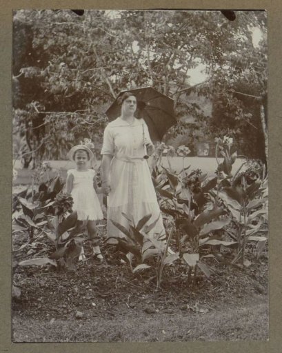 Woman with parasol and child in a garden in the Dutch East Indies