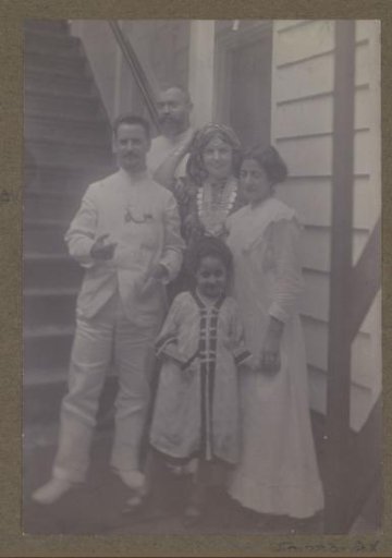 Men, women, and a child at a wooden staircase, two possibly dressed in Eastern costumes