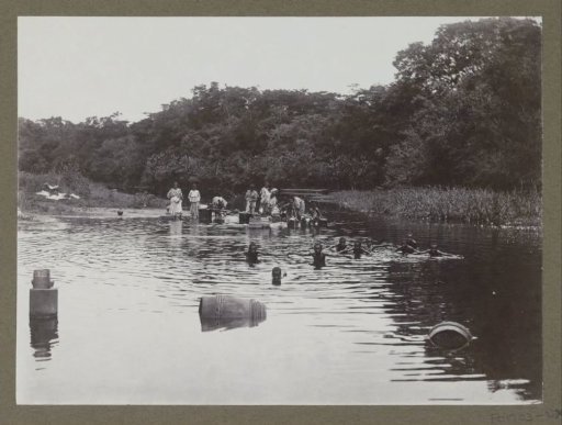 Group of women and children standing and swimming in a river, possibly in Suriname