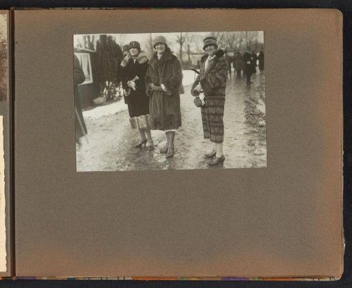 Three women in winter coats on a muddy path