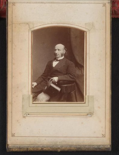 Portrait of a seated man with a top hat in his hand