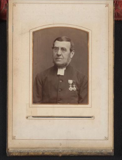 Portrait of a man with spectacles and two insignia on his jacket
