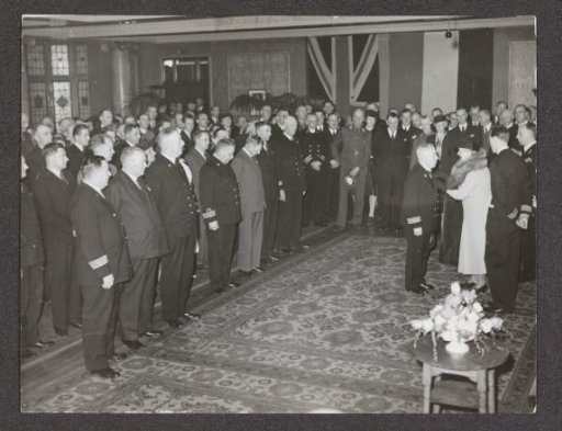 Queen Wilhelmina pinning a decoration on the lapel of an old sailor