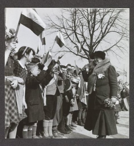 Queen Wilhelmina walking along a hedge of children