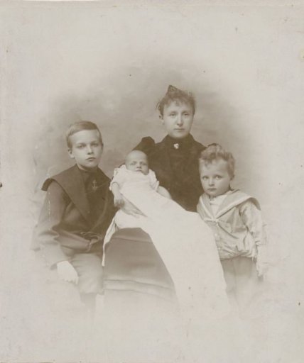 Family portrait of a woman with two boys and a baby in a christening gown