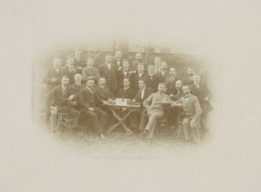 Group portrait of men around a table in a garden