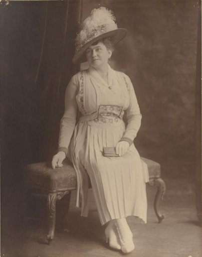 Studio portrait of a seated woman with hat and portfolio