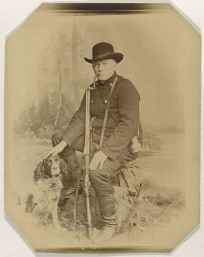 Portrait of a man with hunting dog and rifle in a landscape setting