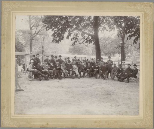 Group portrait of men with bowler hats on garden chairs