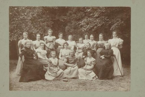 Group portrait of girls and teachers, with tennis rackets and a cricket bat