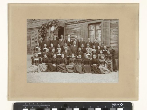 Group portrait of an unknown class in front of a wooden building