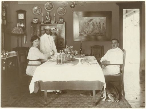 Portrait of an unknown couple at a table with a servant, Dutch East Indies