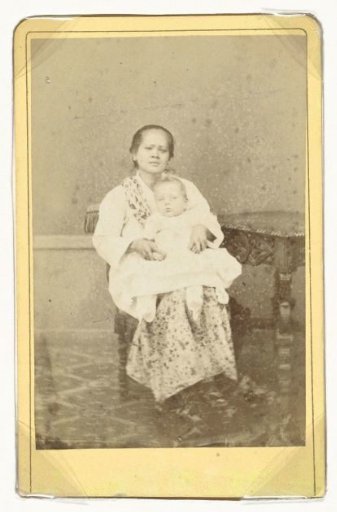 Portrait of an unknown Indonesian child caregiver (then called 'baboe') with baby on lap