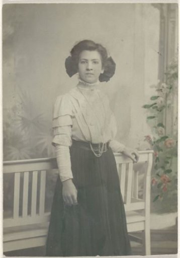 Studio portrait of a young woman by a settee