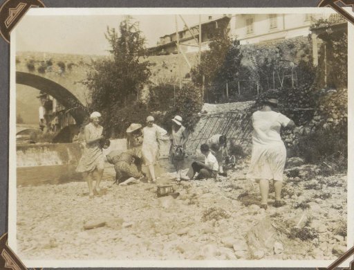 Company at the shore of a waterway near a bridge in a South French town