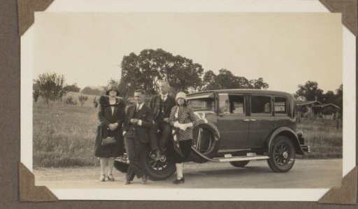 Two women and two men by a car